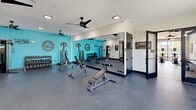 Located at 110 Woodcrest Rd in Cherry Hill, NJ, this well-appointed fitness center offers a expansive single-floor exercise space designed to support a full range of workout routines. The facility is divided into distinct functional zones, providing dedicated areas for both cardiovascular training and strength work.

The cardio area features a row of treadmills, ellipticals, rowing machines, and a stair climber, all positioned near large windows that invite ample natural light and offer views of the surrounding community. Motivational wall art and bold teal accent walls energize the atmosphere throughout the space.

The strength training section is equally comprehensive, equipped with cable machines, multi-functional cable towers, adjustable benches, and a full rack of dumbbells. Floor-to-ceiling mirrors line portions of the walls, enhancing the sense of openness and aiding proper form during workouts. A dedicated functional training area includes a storage rack stocked with medicine balls, resistance equipment, and a heavy bag, ideal for dynamic and high-intensity training sessions.

Throughout the facility, durable rubberized flooring provides safety and comfort, while multiple ceiling fans ensure consistent air circulation. Black-framed glass doors and large windows connect the interior to its surroundings, contributing to a bright, modern aesthetic that makes this fitness center a well-rounded and motivating environment for exercise.