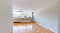 Located at 552 Birchmount Rd, Unit 208 in Toronto's Scarborough neighbourhood, this 2-bedroom, 1-bathroom unit offers a practical and well-organized layout on a single floor. Warm parquet flooring flows consistently throughout the living areas and bedrooms, adding a classic character to the space.

The generously proportioned primary bedroom is a standout feature, offering ample room for furnishings and benefiting from large windows that allow natural light to pour in while framing views of the surrounding neighbourhood. The second bedroom is similarly finished with the same parquet flooring, neutral grey walls, and a built-in sliding-door closet, providing convenient storage.

The main living area is open and bright, anchored by a wide bank of windows fitted with a baseboard heating unit, offering both warmth and an outlook onto lush greenery. The kitchen is positioned efficiently along one wall, with white cabinetry providing functional storage.

The bathroom is clean and simply appointed, featuring a full soaker tub with a tiled surround in white horizontal tiles and chrome fixtures. A hallway connects the rooms and provides a smooth transition throughout the unit. Overall, the space presents a bright, neutral, and move-in ready environment well-suited for comfortable everyday living.