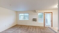 Located at 4596 Idewild Loop in Coeur d'Alene, Idaho, this two-bedroom, one-bathroom residence offers a practical and comfortable layout across a single level. The open-concept living, dining, and kitchen area forms the heart of the home, with a breakfast bar peninsula separating the kitchen from the carpeted living space. The kitchen is well-appointed with warm wood cabinetry, white countertops, hardwood-style flooring, and black appliances including a range, dishwasher, and refrigerator, all centered around a window that brings in natural light. The living room features sliding glass doors leading to a private balcony, which overlooks the surrounding community and tree-lined scenery. A second window further brightens the space. The primary bedroom is generously sized, also offering sliding glass door access to the balcony, while the second bedroom features carpeting and a window with neighborhood views. The full bathroom is clean and functional, featuring a tub-shower combination, hardwood-style flooring, and a window for ventilation. A dedicated closet provides additional storage. Carpeted stairs connect to the entry level, and the overall interior palette of soft neutrals and warm wood tones creates a cohesive, move-in-ready atmosphere throughout.