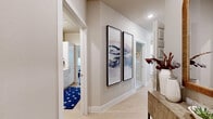 This thoughtfully designed two-bedroom, two-bathroom home in Sherman, Texas offers a cohesive blend of modern aesthetics and practical living across a single floor. The open-concept kitchen and living area serves as the heart of the home, where crisp white cabinetry, a herringbone tile backsplash, and stainless steel appliances create a sleek culinary space. A generous peninsula with a quartz countertop and bar seating flows effortlessly into the living room, which is bathed in natural light from multiple windows and features light wood-style flooring, a ceiling fan, and a welcoming, neutral palette. A well-lit hallway with vaulted ceilings connects the main living areas to the private bedrooms, each offering natural light through large windows with classic shutters. The primary bedroom includes a dedicated en-suite bathroom featuring a long white vanity, framed mirror, light wood flooring, and a glass-enclosed walk-in shower. The second bathroom mirrors this clean, contemporary style. Both bedrooms are served by dedicated closets. A separate in-unit laundry area adds everyday convenience. Throughout, warm neutral tones, recessed lighting, and consistent finishes create a cohesive and inviting atmosphere.
