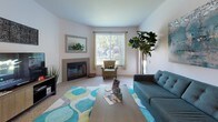 This single-floor residence offers a thoughtfully designed layout across several comfortable living spaces. The living room serves as a central gathering area, featuring a tiled fireplace, large windows that invite abundant natural light, and neutral carpet flooring. A decorative mirror above the fireplace adds depth to the room, while the open feel makes it an inviting space for relaxing or entertaining.

The kitchen is well-equipped with stainless steel appliances, including a range, refrigerator, and dishwasher. White cabinetry with light wood trim lines the walls, providing generous storage, while light countertops and wood-style flooring complete the functional and clean aesthetic.

The residence includes multiple bedrooms, each carpeted and featuring large windows with vertical blinds that allow for natural light and privacy. One bedroom benefits from mirrored sliding closet doors, enhancing the sense of space. The bedrooms offer comfortable proportions suitable for full or queen-sized beds.

Two bathrooms serve the residence: one features a vanity with a large mirror, overhead lighting, and wood-style flooring, while the second is a full bath with a shower/tub combination. Both are finished in a clean, neutral palette. The overall design of the home is bright and functional, with a consistent use of light tones throughout.