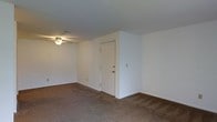Located at 1741 Lucille Dr in Lima, Ohio, this single-floor residential space offers a clean and functional layout well-suited for comfortable everyday living. The interior features wall-to-wall carpeting in a warm neutral tone throughout the main living area, providing a cozy and cohesive feel underfoot. White walls keep the space bright and neutral, offering a versatile backdrop that accommodates a variety of décor styles. A ceiling fan with a built-in light fixture is centrally positioned overhead, providing both air circulation and ambient lighting to the room. The space includes a solid interior door, likely leading to an additional room or storage area, contributing to the overall utility of the layout. Baseboard trim lines the perimeter of the room, adding a subtle finishing detail to the clean, understated interior. The overall ambiance is modest and practical, making it a low-maintenance space with a straightforward, move-in-ready character. With its single-story design, the layout promotes ease of accessibility and navigation throughout.