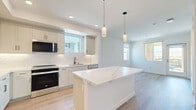 Located at 1151 Encanto Loop in Chula Vista, CA, this thoughtfully designed 1-bedroom, 1-bathroom residence offers a bright and modern living experience. The open-concept kitchen and living area serves as the heart of the home, anchored by a striking quartz waterfall island with elegant veining. The kitchen is outfitted with crisp white shaker cabinetry, a subway tile backsplash, stainless steel appliances including a refrigerator, range, microwave, and dishwasher, and stylish pendant lighting. Light-toned hardwood flooring runs throughout, enhancing the airy, clean aesthetic. Multiple windows allow natural light to fill the space, creating a welcoming ambiance. The bedroom is a comfortable, sun-filled retreat featuring a ceiling fan, large windows with neighborhood views, and access to an outdoor balcony. A dedicated walk-in closet with wire shelving provides ample storage. The full bathroom includes a tiled tub-shower combination with clean, neutral finishes. A hallway connects the living areas with ease, and the overall design emphasizes a consistent, modern palette of whites and soft neutrals that makes the space feel open and well-appointed throughout.