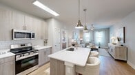 Located at Colonial Gateway Drive in Fort Myers, Florida, this 2-bedroom, 3-bathroom residence offers a thoughtfully designed single-floor layout with a bright, contemporary aesthetic. The open-concept living and kitchen area serves as the heart of the home, featuring light wood-look flooring, neutral tones, and an abundance of natural light from large windows dressed with sheer curtains. The kitchen is appointed with light wood cabinetry, subway tile backsplash, stainless steel appliances, and a central island with a quartz countertop, undermount sink, and seating — illuminated by brushed nickel pendant lights. The living room offers a comfortable, airy atmosphere with a ceiling fan and generous natural light. Both bedrooms are carpeted and well-proportioned, with the primary bedroom providing ample space and access to a dedicated closet. The three bathrooms are finished with white subway tile; one features a walk-in glass shower, while another includes a full soaking tub and shower combo. Two closets with built-in shelving provide organized storage throughout. The overall design is cohesive and modern, presenting a clean, move-in-ready space with quality finishes.