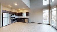 Located at 16624 East Mission Parkway in Spokane Valley, WA, this single-floor unit offers a thoughtfully designed open-concept layout with impressive architectural details. The living area stands out with dramatically high ceilings, a ceiling fan, and a striking wall of floor-to-ceiling windows that flood the space with natural light and frame views of the surrounding neighborhood. Light-toned vinyl plank flooring runs throughout, creating a clean and cohesive look. The kitchen is well-appointed with rich dark-stained cabinetry, granite-look countertops, a classic white subway tile backsplash, and a full suite of stainless steel appliances including a refrigerator, range, over-the-range microwave, and dishwasher. Recessed lighting illuminates the kitchen area, which opens directly to the spacious living area. A utility closet with in-unit laundry hookups adds everyday convenience. The bathroom features light, neutral finishes with a tub-shower combination, a window for natural ventilation, and light plank flooring consistent with the rest of the unit. A second bathroom is also present, offering additional functionality. The overall ambiance is modern, bright, and move-in ready, making this unit a practical and stylish home in Spokane Valley.