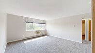 Located at 510 College Ave in Grand Rapids, MI, this single-floor unit offers three bedrooms and one bathroom within a well-organized layout. The spacious primary bedroom features plush carpeting, a built-in closet with warm wood-tone doors, natural light from a wide window with outdoor views, and a wall-mounted air conditioning unit alongside baseboard heating. The two additional bedrooms are similarly carpeted and include baseboard heating, ceiling light fixtures, and windows that bring in natural light. The kitchen stands out as a modern, updated space featuring flat-panel cabinetry in a light wood finish, stainless steel appliances including a refrigerator, range, microwave, and dishwasher, as well as a tile backsplash and light wood-look flooring. The full bathroom is finished with tile flooring in warm earth tones, a tub-shower combination with white tile surround, a vanity with a light countertop, and a mirror. A hallway connects the rooms, contributing to a functional flow throughout the unit. Clean white walls and neutral tones give the space a bright, cohesive aesthetic throughout.