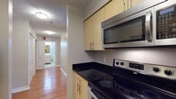 Located at 1450 Washington Blvd in Stamford, Connecticut, this single-floor residence offers a thoughtfully designed layout with consistent finishes throughout. Rich hardwood flooring flows seamlessly across the living areas and bedrooms, lending warmth and cohesion to the space.

The kitchen is equipped with stainless steel appliances, including an electric range and an over-the-range microwave, complemented by sleek black granite countertops and light wood cabinetry that provides ample storage. The layout connects efficiently to the rest of the unit via a well-lit hallway.

The living area is generously sized, featuring neutral gray walls, bright windows with roller shades that invite natural light, and a baseboard heating unit. The open feel of the room offers flexible arrangement possibilities.

Both bedrooms are comfortably proportioned, each featuring hardwood floors, neutral-toned walls, and closets with paneled doors — one with a double-door closet and another with a walk-in style closet outfitted with shelving.

The bathrooms are finished with warm-toned tile flooring, a tub-shower combination with white tile surround, a vanity with under-sink cabinetry, a wall mirror, and clean white fixtures throughout. The overall design is practical and move-in ready, reflecting a clean and functional aesthetic suitable for everyday living.