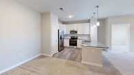 Located at 15010 Flagpole Dr in Charlotte, NC, this well-appointed 2-bedroom, 2-bathroom residence offers a thoughtfully designed single-floor layout. The kitchen serves as a central highlight, showcasing granite countertop surfaces, white shaker-style cabinetry, a subway tile backsplash, stainless steel appliances including a refrigerator with ice maker, range, and microwave, along with a peninsula island illuminated by stylish pendant lighting — ideal for both meal prep and casual dining. Wood-look flooring runs throughout the kitchen and dining area, transitioning to plush carpet in the living and bedroom spaces. The spacious primary bedroom features a ceiling fan, a large window overlooking the neighborhood, and direct access to a walk-in closet outfitted with multi-tier wire shelving. The primary bathroom is equipped with a dual-sink granite vanity, white cabinetry, and a glass-enclosed walk-in shower with wood-look flooring. The second bedroom also offers a ceiling fan and generous natural light. The secondary bathroom includes a granite vanity and a full tub-shower combination. A dedicated laundry room houses a full-size washer and dryer with overhead shelving, adding everyday convenience to this complete and functional Charlotte home.
