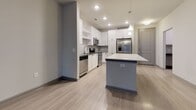 This single-floor residence in Sandy Springs, GA (30328) offers a well-designed open-concept layout that seamlessly connects the kitchen, dining, and living areas. The kitchen is outfitted with crisp white shaker cabinetry, a gray subway tile backsplash, stainless steel appliances including a range, microwave, dishwasher, and refrigerator, and a generously sized quartz peninsula that provides ample workspace and casual seating. Light wood-look flooring extends throughout the main living areas, contributing to a clean, modern aesthetic.

The living area is spacious and bright, anchored by a set of French doors with transom windows that invite natural light and provide access to an outdoor space. A second living or flex area features similar light flooring and direct exterior access through a framed glass door with sidelights.

Bedrooms are carpeted for comfort and include large windows that frame views of surrounding greenery. At least one bedroom features direct access to a walk-in closet with built-in shelving. The bathroom is finished with light wood-look tile flooring, white shaker-style cabinetry topped with a dark stone countertop, and a full tub-shower combination with white subway tile surround and brushed nickel fixtures.