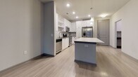 This single-floor residence in Sandy Springs, GA (30328) offers a well-designed open-concept layout that seamlessly connects the kitchen, dining, and living areas. The kitchen is outfitted with crisp white shaker cabinetry, a gray subway tile backsplash, stainless steel appliances including a range, microwave, dishwasher, and refrigerator, and a generously sized quartz peninsula that provides ample workspace and casual seating. Light wood-look flooring extends throughout the main living areas, contributing to a clean, modern aesthetic.

The living area is spacious and bright, anchored by a set of French doors with transom windows that invite natural light and provide access to an outdoor space. A second living or flex area features similar light flooring and direct exterior access through a framed glass door with sidelights.

Bedrooms are carpeted for comfort and include large windows that frame views of surrounding greenery. At least one bedroom features direct access to a walk-in closet with built-in shelving. The bathroom is finished with light wood-look tile flooring, white shaker-style cabinetry topped with a dark stone countertop, and a full tub-shower combination with white subway tile surround and brushed nickel fixtures.