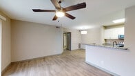 This single-floor residence offers a clean, modern aesthetic highlighted by light hardwood-style flooring that runs consistently throughout the entire space. The open-concept living and dining area is bright and airy, featuring a ceiling fan with integrated lighting and a sliding glass door fitted with vertical blinds that allows natural light to fill the room.

The kitchen is thoughtfully designed with white upper cabinetry, gray lower cabinetry, granite countertops, and a full suite of stainless steel appliances including a range, microwave, refrigerator, and dishwasher. A peninsula counter with matching granite serves as both a functional workspace and a natural divider between the kitchen and living area, complemented by a pendant light fixture overhead. A louvered closet door within the kitchen provides additional storage.

The bedrooms are comfortably sized, each featuring windows with blinds that invite natural light. One bedroom includes a walk-in closet with built-in shelving, offering generous storage capacity. The bathrooms are finished with granite-top vanities, framed mirrors, and white tile surrounds in the tub-shower combination, maintaining a cohesive and updated look throughout the home.