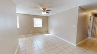 This single-story home offers a practical and cohesive layout with consistent light tile flooring running throughout every room, creating a clean, unified look. Warm neutral-toned walls complement the bright, airy feel found across the living spaces.

The main living area is generously sized, featuring a ceiling fan with light fixture, a textured ceiling, and multiple windows dressed with blinds that allow natural light to filter in comfortably. An adjacent room — suitable as a dining area or secondary living space — mirrors this design with its own ceiling fan and windows on two sides, enhancing the sense of openness.

The galley-style kitchen is well-appointed with warm wood cabinetry extending to the ceiling, granite-look countertops, a double stainless steel sink, and white appliances including a refrigerator and range. A window at the far end of the kitchen brings in additional natural light.

The bedrooms are well-proportioned, each featuring the same neutral palette, tiled floors, textured ceilings, and windows with blinds. One bedroom includes a built-in closet with bifold doors and a ceiling fan. The full bathroom is functional and neatly finished, featuring a tub and shower combination, a wood-framed vanity mirror, white countertop, and tile flooring consistent with the rest of the home.