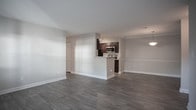 Located at 638 River Bend Ct in Newport News, Virginia, this single-floor residence offers a well-organized layout with a clean, modern aesthetic throughout. The galley-style kitchen is a standout feature, showcasing rich dark cabinetry, granite-look countertops, a white subway tile backsplash, and stainless steel appliances including a range, microwave, and refrigerator. Light wood-look vinyl flooring runs the length of the kitchen, adding warmth and easy maintenance.

The open living and dining area is expansive, finished with dark wood-look plank flooring that contrasts beautifully with the neutral gray walls and bright white trim. A window allows natural light to filter in, enhancing the airy feel of the space. A built-in pass-through to the kitchen keeps the layout connected and functional.

The bedrooms are carpeted and generously proportioned, each receiving ample natural light through sizable windows with blinds. The primary bedroom includes access to a walk-in closet and an en-suite bathroom. Both bathrooms are finished with wood-look tile flooring and include soaking tubs with shower combinations, dark vanity cabinetry, and clean white fixtures, offering a practical yet polished feel throughout.