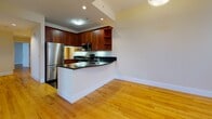 Located at 227 Church Street within The Eli in New Haven, Connecticut, this single-floor residence offers a thoughtfully designed layout with consistent warm hardwood flooring throughout. The open-concept living and dining area is bright and airy, with natural light streaming in through large windows fitted with blinds. A peninsula-style kitchen flows seamlessly into the living space, featuring rich dark wood cabinetry, dark granite countertops, stainless steel appliances including a refrigerator, range, and microwave, and an eat-in bar that makes it ideal for both cooking and entertaining. The bedrooms are generously proportioned with clean cream-toned walls, gleaming hardwood floors, and multiple windows that invite natural light and city views. The bathrooms offer a striking contrast with polished dark granite tile flooring, pedestal sinks, large mirrors with vanity lighting, and a walk-in tiled shower. A dedicated walk-in closet with built-in shelving provides ample storage adjacent to the bathroom. The neutral color palette and clean architectural lines throughout the unit create a cohesive, modern ambiance well-suited to a variety of lifestyles. Situated in the heart of New Haven, The Eli places residents close to Yale University, local dining, cultural attractions, and public transit.