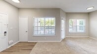 Located at 2511 Farmcrest Dr in Herndon, VA, this one-bedroom, one-bathroom unit offers a well-designed single-floor layout. The combined kitchen and living room forms the heart of the home, where warm carpet flooring transitions to light hardwood-style flooring near the entryway. A black tile-surround fireplace anchors the living area, while multiple windows flood the space with natural light and offer views of the surrounding tree-lined community. The kitchen is outfitted with white shaker-style cabinetry, granite countertops, stainless steel appliances including a refrigerator, range, microwave, and dishwasher, and a peninsula with a built-in sink that opens to the living area. A skylight above the kitchen adds additional brightness. The bedroom features plush carpeting, neutral walls, and a window with a view of the greenery outside. The full bathroom includes wood-style flooring, white cabinetry with granite countertops, a large mirror, and a tub-shower combination with white tile surround. A dedicated closet and hallway complete the interior layout. A private balcony with a wood deck and railing offers pleasant outdoor views of mature trees and the surrounding neighborhood.