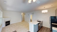 This well-appointed single-floor residence offers a thoughtfully designed layout that balances comfort and functionality. The open-concept living and dining area is bathed in natural light streaming through large windows and a glass door, which leads to the outdoors. A ceiling fan overhead and a classic fireplace with a white mantel add warmth and character to the living space. Durable wood-look flooring flows through the kitchen and entry areas, transitioning into plush carpeting throughout the living and bedroom spaces.

The kitchen is a standout feature, boasting gray shaker-style cabinetry, gleaming quartz countertops, and a suite of stainless steel appliances including a gas range, microwave, refrigerator, and dishwasher. An elegant chandelier adds a refined touch above the peninsula, which doubles as a casual dining or prep space.

The bedrooms are generously sized, with soft carpeting, ample natural light, and direct access to spacious walk-in closets with wire shelving systems. The primary bedroom connects to an en-suite bathroom, while a second full bathroom serves the rest of the residence. Both bathrooms feature tub-shower combos, quartz vanity countertops, and clean, neutral finishes throughout. The overall ambiance is bright, fresh, and move-in ready.