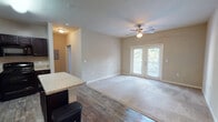 Located in Jacksonville, FL (32205), this single-floor unit offers a thoughtfully designed layout that balances functionality and comfort. The open-concept living area is a central highlight, featuring warm neutral tones, plush carpeting, and wood-look flooring that transitions seamlessly between spaces. A ceiling fan adds both style and practicality, while a set of French doors floods the room with natural light and provides access to an outdoor balcony with views of surrounding greenery.

The kitchen is well-appointed with rich, dark espresso cabinetry, granite-style countertops, a center island, and a full suite of black appliances including a refrigerator, range, microwave, and dishwasher. Wood-look flooring extends throughout the kitchen and entry area, adding a cohesive, polished look. Ample cabinetry ensures generous storage throughout.

The bedroom features soft carpeting, neutral wall tones, and a ceiling fan, creating a calm and restful environment. The bathroom is finished with tile surround in the tub/shower combination, wood-look flooring, a dark vanity with granite-style countertop, and brushed nickel fixtures. Additional features include an in-unit entry closet and utility access, contributing to the overall practicality of this well-maintained Jacksonville residence.