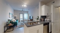 This 1-bedroom, 1-bathroom residence is thoughtfully designed to maximize every square foot of its single-floor layout. The open-concept kitchen and living area serves as the heart of the home, where a sleek kitchen features white cabinetry, dark granite countertops with a double-basin stainless steel sink, a dark tile backsplash, and a full suite of stainless steel appliances including a refrigerator, electric range, microwave, and dishwasher. The kitchen flows seamlessly into the living space, which is bathed in natural light from large windows dressed with sheer curtains and horizontal blinds. A ceiling fan adds both comfort and function to the living area. The bedroom is a serene retreat, highlighted by a generously sized window that fills the room with soft, natural light. It includes a dedicated closet with built-in shelving and direct access to the hallway. The full bathroom is clean and bright, featuring a tiled tub-shower combination, overhead cabinetry for storage, and light tile flooring. Throughout the residence, the neutral color palette, light flooring, and crisp white walls create a cohesive, modern ambiance that is both airy and inviting.