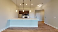 Located at 44 Veterans Memorial Dr in Somerville, NJ, this single-floor unit offers a thoughtfully designed open-concept layout with contemporary finishes throughout. The kitchen serves as a central focal point, anchored by a large island with a sleek quartz countertop and an undermount sink. Pendant lights hang above the island, adding a stylish touch, while dark espresso cabinetry provides strong visual contrast. Stainless steel appliances, including a refrigerator, range, and microwave, complete the well-appointed kitchen space.

The open living area flows seamlessly from the kitchen, featuring warm hardwood-style flooring and neutral toned walls that create a bright, welcoming ambiance. A ceiling fan and recessed lighting keep the space comfortable, while a sliding glass door opens to a private balcony offering outdoor views of surrounding greenery.

The bedrooms are calm and understated, benefiting from natural light through well-placed windows that frame views of the tree line. The bathroom is finished with tile flooring and surround, a dark vanity with a white countertop, and a tub-shower combination. Consistent flooring, clean trim work, and a cohesive neutral palette unify the overall design of the space.