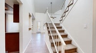 Located at 2600 W Ina Rd in Tucson, Arizona, this two-story residence offers a well-designed layout with a variety of functional and inviting spaces throughout both levels. The entry foyer immediately impresses with its dramatic vaulted ceiling height, setting a grand tone carried through the main living area. A ceiling fan hangs overhead in the spacious living room, which features warm wood-look laminate flooring, a classic corner fireplace with a tile surround, and tall walls that amplify the sense of openness. Natural light filters in through multiple windows fitted with horizontal blinds, brightening the open layout. A sliding glass door provides direct access to the outdoors. The kitchen is outfitted with rich dark wood cabinetry, granite-style countertops, a full suite of stainless steel appliances including a refrigerator, electric range, microwave, and dishwasher, as well as a window above the sink. Upstairs, the carpeted bedrooms offer a quiet retreat, each with ample natural light from well-placed windows. The primary bedroom features a ceiling fan and a generously sized walk-in closet with wire shelving. The bathroom includes wood-look vinyl flooring, a soaking tub, and tile-surround walls. This residence combines practical amenities with comfortable, open living spaces suited for everyday life in Tucson.