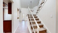 Located at 2600 W Ina Rd in Tucson, Arizona, this two-story residence offers a well-designed layout with a variety of functional and inviting spaces throughout both levels. The entry foyer immediately impresses with its dramatic vaulted ceiling height, setting a grand tone carried through the main living area. A ceiling fan hangs overhead in the spacious living room, which features warm wood-look laminate flooring, a classic corner fireplace with a tile surround, and tall walls that amplify the sense of openness. Natural light filters in through multiple windows fitted with horizontal blinds, brightening the open layout. A sliding glass door provides direct access to the outdoors. The kitchen is outfitted with rich dark wood cabinetry, granite-style countertops, a full suite of stainless steel appliances including a refrigerator, electric range, microwave, and dishwasher, as well as a window above the sink. Upstairs, the carpeted bedrooms offer a quiet retreat, each with ample natural light from well-placed windows. The primary bedroom features a ceiling fan and a generously sized walk-in closet with wire shelving. The bathroom includes wood-look vinyl flooring, a soaking tub, and tile-surround walls. This residence combines practical amenities with comfortable, open living spaces suited for everyday life in Tucson.