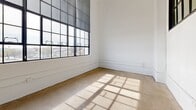 Located at 424 Memorial Dr in Danville, VA, this 2-bedroom, 1-bathroom unit offers a striking industrial-modern aesthetic rooted in its architectural character. The open-concept living and dining area is anchored by soaring ceilings with exposed ductwork, polished concrete floors, and oversized black-framed factory windows that flood the space with natural light and offer sweeping views of the surrounding cityscape.

The kitchen flows seamlessly into the living area and features granite countertops, a breakfast bar peninsula, taupe cabinetry, and a full suite of stainless steel appliances. Pendant lighting adds a warm, contemporary touch to the space.

Both bedrooms are generously sized, with the primary bedroom benefiting from tall ceilings, a ceiling fan, and a walk-in closet. The second bedroom mirrors the unit's signature aesthetic with expansive factory windows and abundant natural light. The full bathroom is finished with granite countertops, dark cabinetry, and a tub-shower combination. A dedicated laundry room with a full-size washer and dryer adds everyday convenience. Two closets provide additional storage throughout the unit. The overall ambiance is bright, open, and distinctly urban, blending historical industrial character with modern finishes.