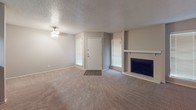 This single-floor residence offers a thoughtfully designed layout that balances comfort and functionality. The living area is generously sized, featuring plush wall-to-wall carpeting, neutral-toned walls, and a textured ceiling that adds subtle character. Natural light filters in through multiple windows dressed with blinds, and a ceiling fan provides year-round comfort. A classic fireplace with a white mantel serves as a focal point, lending warmth and charm to the space.

The kitchen is efficiently arranged with dark cabinetry contrasted by light granite-style countertops that wrap around the workspace. A stainless steel sink, an electric range, and a dedicated pantry door contribute to its practicality, while wood-look flooring ties the aesthetic together seamlessly.

The bathroom continues the dark cabinetry theme, featuring an extended vanity with a large framed mirror and a well-lit fixture overhead. A granite-topped countertop with an undermount sink, wood-look flooring, and a shower-tub combination complete the space with a clean, cohesive finish.

The entryway provides a welcoming transition into the home, with hard flooring that leads naturally into the main living areas. Throughout the residence, a consistent neutral color palette and coordinated finishes create a cohesive and move-in-ready environment.