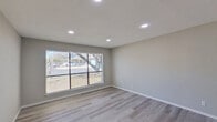This thoughtfully updated two-story home showcases a clean, modern aesthetic carried consistently throughout both levels. Light gray luxury vinyl plank flooring runs through the living areas and bedrooms, providing a cohesive and contemporary foundation underfoot. The open living area features large sliding windows framed by horizontal blinds, inviting generous natural light and offering views of mature trees outside, while recessed lighting provides bright, even illumination after dark.

The kitchen is well-appointed with crisp white shaker cabinets, granite countertops with subtle veining, a subway tile backsplash, and a full suite of stainless steel appliances, including a flat-top range, over-the-range microwave, and dishwasher.

Multiple bedrooms are spread across both floors, each featuring neutral gray walls, vinyl plank flooring, and window blinds. Several rooms are equipped with ceiling fans for added comfort. The bathroom presents a clean, functional design with a tub-shower combination, white tile surround, a vanity with understated cabinet hardware, and matching flooring that ties the space together.

Throughout the home, white trim and neutral wall tones create a bright, move-in-ready atmosphere well-suited for a variety of living arrangements.