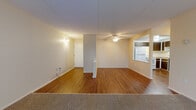 Located at 11883 Pearl Rd in Strongsville, Ohio, this single-floor unit offers a practical and well-organized layout. The main living area features a combination of wood-look hardwood flooring and plush carpeting, creating a clear distinction between spaces. A ceiling fan overhead adds comfort, while baseboard heating and a wall-mounted air conditioning unit ensure year-round climate control. Large vertical blinds along one wall allow for adjustable natural light. A half-wall partition subtly defines the transition between the living and adjacent areas.

The kitchen is equipped with dark wood cabinetry offering ample upper and lower storage, light granite-style countertops, a white electric range, refrigerator, and a black dishwasher. Wood-look flooring continues throughout this space, and a pass-through window connects it to the main living area.

The bedroom features neutral carpeting and includes two separate closets, each with a hanging rod and shelf, providing generous storage. An additional carpeted room with its own closet offers flexible use as a second bedroom or den.

The bathroom is finished with stone-look tile flooring, white cabinetry with a single sink, a mirrored medicine cabinet, and a full tub and shower surrounded by white square tile.
