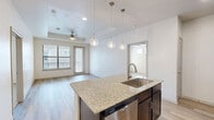 Located at 4900 Windhaven Pkwy in Lewisville, TX, this single-floor, 2-bedroom, 1-bathroom residence offers a thoughtfully designed layout with contemporary finishes throughout. The open-concept kitchen and living area serves as the heart of the home, featuring a large granite-topped island with an undermount sink, dark espresso cabinetry, stainless steel appliances, and stylish pendant lighting. Light wood-style flooring runs through the main living areas, creating a warm and cohesive aesthetic. The living room is bright and airy, with a ceiling fan, a generous window, and direct access to a private balcony that allows natural light to fill the space. The spacious primary bedroom features plush carpeting, a ceiling fan, a bank of three windows with outdoor views, and direct access to the shared bathroom. The second bedroom is comfortably sized with soft carpet, a closet, and its own window. The full bathroom is well-equipped with a dual-sink granite vanity, dark cabinetry, a large wall mirror, modern light fixtures, and a full soaking tub with tiled surround. A connecting hallway ties the layout together efficiently, making this a functional and attractive residence.