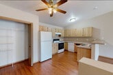 This single-floor, 2-bedroom, 1-bathroom home offers a practical and comfortable layout across a generously sized floor plan. The combined kitchen and living room serves as the heart of the home, featuring warm hardwood-style flooring throughout. The kitchen is well-equipped with light wood cabinetry providing ample storage, a U-shaped countertop layout, a double stainless steel sink, white appliances including a refrigerator, electric range, and dishwasher, and a peninsula that defines the space. A ceiling fan overhead adds to the room's functionality.

The living area is bright and open, benefiting from a sliding glass door that leads to an outdoor deck and an additional window, both offering views of the surrounding natural landscape. Baseboard heating is present throughout the home.

The two bedrooms are carpeted and well-sized, with the primary bedroom featuring a window with outdoor views and an adjacent closet. The second bedroom is similarly appointed with neutral tones and carpeted flooring.

The bathroom includes a wide vanity with oak cabinetry, a large mirror with overhead lighting, and hardwood-style flooring. A hallway connects the main living areas to the bedrooms and bathroom, completing this functional and inviting floor plan.