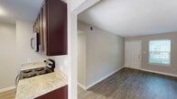 This single-floor residence at 3301 Shannon Rd in Durham, NC offers a thoughtfully laid-out living space with modern finishes throughout. The kitchen is a standout feature, designed in a galley style with rich dark-wood cabinetry providing ample storage, light granite-style countertops, and stainless steel appliances including a refrigerator, electric range, dishwasher, and over-the-range microwave. Light wood-style flooring runs through the kitchen, complementing the neutral wall tones. Adjacent to the kitchen, the combined living and dining area is open and bright, with the same light wood-style flooring continuing seamlessly. A sliding glass door in the dining area allows natural light to pour in and provides direct access to an outdoor space. The living area offers generous room for furnishing and features a second entry door. The bedroom is comfortably sized with plush carpeting, a window with blinds that brings in natural light, and a textured ceiling consistent throughout the home. The bathroom is clean and functional, featuring a full soaking tub with a tile surround, a curved shower rod, and wood-style flooring. Neutral gray tones, white trim, and textured ceilings unify the aesthetic of this well-maintained residence.
