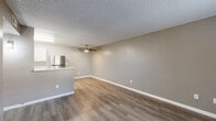 This single-floor unit offers a practical and well-appointed layout designed for comfortable everyday living. The open-concept living and dining area is finished with durable wood-look laminate flooring and neutral taupe-toned walls, creating a clean and cohesive aesthetic. A ceiling fan overhead adds functionality, while a textured ceiling is consistent throughout the space. The kitchen is efficiently designed in a U-shaped configuration, featuring crisp white cabinetry with modern hardware, light stone-look countertops, a peninsula with bar seating, and stainless steel appliances including a refrigerator and an electric range. Natural light filters into the main living area through a window fitted with blinds, contributing to a bright and welcoming atmosphere. The bedrooms are carpeted for added comfort and warmth, each featuring the same neutral wall tones and windows with blinds that allow for natural light and privacy. The bathroom includes a full tub-shower combination, a toilet, and a vanity with a granite-style countertop. Throughout the unit, clean white baseboards and consistent finishes tie each room together, resulting in a cohesive and move-in ready space.