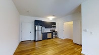 Located at 6300 City Avenue in Philadelphia, PA, this single-floor unit offers a clean, modern aesthetic defined by an open-concept layout and thoughtful design details throughout. The kitchen is a standout feature, equipped with stainless steel appliances including a refrigerator, range, microwave, and dishwasher. Deep navy cabinetry provides a striking contrast against the white subway tile backsplash and crisp white walls, creating a contemporary yet inviting atmosphere. A deep sink and ample counter space make the kitchen both functional and stylish. Warm hardwood flooring runs throughout the space, adding natural texture and a sense of continuity between areas. The open floor plan allows for flexible living arrangements, with generous room to define both a living and dining area. A walk-in closet offers substantial storage, adding practicality to the unit's modern appeal. Flush ceiling lighting provides consistent illumination throughout the interior. The white walls and light-toned flooring work together to maximize the sense of brightness and openness. Overall, this space combines practical amenities with a polished, contemporary design, making it a well-appointed residence in the City Avenue corridor of Philadelphia.