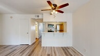 Located on Vincennes Street in the Northridge neighborhood of Los Angeles, this one-bedroom, two-bathroom unit offers a well-organized single-floor layout designed for efficient, comfortable living. Light wood-tone flooring runs throughout the entire space, lending a clean, cohesive look to every room.

The open-concept living and kitchen area serves as the heart of the unit. A peninsula with a light stone-style countertop separates the kitchen from the living space, providing both workspace and casual seating. The kitchen is outfitted with stainless steel appliances — including a gas range, over-the-range microwave, and refrigerator — along with white cabinetry, a double-basin sink, and a dishwasher. A ceiling fan with integrated lighting fixture anchors the living area above.

The bedroom is a quiet, naturally lit space featuring a large sliding window that frames views of the surrounding greenery, allowing sunlight to fill the room throughout the day. White walls and the continuous wood flooring keep the aesthetic simple and inviting.

Both bathrooms are finished in a clean, minimal style consistent with the rest of the unit, featuring white cabinetry and light countertops. The overall design of the space prioritizes clean lines, neutral tones, and practical functionality throughout.