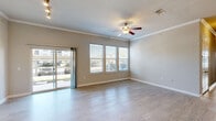 Located in Little Elm, TX, this well-appointed single-story home offers four bedrooms and five bathrooms across a generously sized floor plan. The open living room is bright and welcoming, featuring light wood-look flooring, crown molding, a ceiling fan, and large windows alongside a sliding glass door that fills the space with natural light and provides outdoor views. An additional connected living area shares the same polished aesthetic.

The kitchen is a standout feature, showcasing rich dark cabinetry with raised-panel detailing, granite countertops, a tile backsplash, stainless steel appliances including a refrigerator, range, and built-in microwave, and an island with additional counter space.

The bedrooms are finished with the same light wood-look flooring, crown molding, and ceiling fans, offering a clean and cohesive feel throughout. Several bedrooms include closets with double doors. The bathrooms are well-appointed with granite vanity tops, dark cabinetry, and tile-surround tub-shower combinations. One bathroom features a glass-enclosed walk-in shower with large-format tile and contemporary chrome fixtures.

The entrance foyer leads smoothly into the main living areas, and a covered patio provides a comfortable outdoor transition with views of the landscaped surroundings and covered parking area.