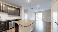 Located at 120 Chubb Ave in Lyndhurst, NJ, this well-appointed two-bedroom, two-bathroom residence offers a thoughtfully designed single-floor layout. The open-concept kitchen is a standout feature, showcasing rich dark espresso cabinetry, a classic subway tile backsplash, sleek light quartz countertops, a central island, and a full suite of stainless steel appliances including a refrigerator, range, microwave, and dishwasher. The kitchen flows seamlessly into the living room, which is bathed in natural light and anchored by wood-style plank flooring throughout. Sliding glass doors lead to a private balcony with views of the surrounding neighborhood. The spacious primary bedroom features its own closet, while the second bedroom is finished with plush carpeting and ample storage access. Both bathrooms are appointed with dark vanity cabinetry, light countertops, and clean tile flooring. A dedicated in-unit laundry room houses a stacked washer and dryer, adding everyday convenience. Neutral wall tones and consistent finishes throughout create a cohesive and modern aesthetic across the entire residence.