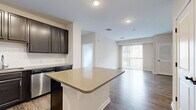 Located at 120 Chubb Ave in Lyndhurst, NJ, this well-appointed two-bedroom, two-bathroom residence offers a thoughtfully designed single-floor layout. The open-concept kitchen is a standout feature, showcasing rich dark espresso cabinetry, a classic subway tile backsplash, sleek light quartz countertops, a central island, and a full suite of stainless steel appliances including a refrigerator, range, microwave, and dishwasher. The kitchen flows seamlessly into the living room, which is bathed in natural light and anchored by wood-style plank flooring throughout. Sliding glass doors lead to a private balcony with views of the surrounding neighborhood. The spacious primary bedroom features its own closet, while the second bedroom is finished with plush carpeting and ample storage access. Both bathrooms are appointed with dark vanity cabinetry, light countertops, and clean tile flooring. A dedicated in-unit laundry room houses a stacked washer and dryer, adding everyday convenience. Neutral wall tones and consistent finishes throughout create a cohesive and modern aesthetic across the entire residence.