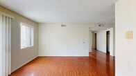 Located at 843 Irolo St in the heart of Los Angeles, CA, this one-bedroom, one-bathroom unit offers a well-organized single-floor layout designed for comfortable city living. Warm hardwood-style flooring runs throughout the main living areas, lending a cohesive and inviting feel to the entire space.

The living room is a bright, open area bathed in natural light, courtesy of a sliding glass door fitted with vertical blinds and an adjacent window. The neutral, cream-toned walls provide a clean backdrop and complement the rich flooring underfoot. A textured ceiling adds a classic finishing touch consistent throughout the unit.

The bedroom is a generously sized private retreat featuring a large window with vertical blinds, a double sliding-door closet offering ample storage, and the same warm flooring found throughout. The room is well-lit and comfortable, providing a quiet escape from the bustle of the city.

The galley-style kitchen is efficiently laid out with white cabinetry, dark countertops, and a white gas range, offering practical functionality in a compact footprint. Light-toned flooring in the kitchen contrasts cleanly with the cabinetry.

The bathroom features a wood-toned vanity with a white countertop, modern chrome fixtures, and a mirrored medicine cabinet, creating a clean and functional space. A hallway connects the rooms, completing this well-planned urban residence.