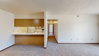 Located at 1700 Mall Road in Monroe, Michigan, this single-floor, 2-bedroom, 1-bathroom unit offers a functional and well-organized layout. The open-concept living and dining area is carpeted and bathed in natural light from a large window, with a baseboard heating system providing warmth throughout. A half-wall peninsula with warm wood-toned paneling connects the living space to the kitchen, creating an open, airy feel while maintaining a clear visual separation between areas.

The galley-style kitchen is efficiently designed with white cabinetry featuring wood-trimmed accents, ample upper and lower storage, white appliances including a refrigerator and range, a single-basin sink, and light tile flooring that contrasts nicely with the carpeted living areas.

The primary bedroom is generously sized, featuring a ceiling fan, two side-by-side closets, and a window that brings in natural outdoor views. The second bedroom is a comfortable space with its own closet and window. A hallway with additional closet storage connects the bedrooms to the full bathroom, which includes a single-sink vanity with cabinetry, a large mirror, tile flooring, and a baseboard heater. Throughout the unit, warm wood door trims and neutral walls create a cohesive and practical living environment.