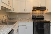 Located at 1723 Fairfax Rd in Greensboro, NC, this single-story unit offers a well-appointed layout with a variety of functional and aesthetic details throughout. The kitchen is a standout feature, outfitted with white shaker-style cabinetry, granite-look countertops, a decorative tile backsplash, and black appliances including a range, dishwasher, and refrigerator. Wood-look plank flooring runs through the kitchen and living areas, adding warmth and continuity to the space.

The living area is generously sized and benefits from natural light streaming through a large sliding glass door that opens onto a private balcony with outdoor views. A striking exposed brick accent wall adds architectural character to one end of the living space. Ceiling fans are present throughout, promoting airflow and comfort.

The bedrooms are carpeted and each features a ceiling fan and natural light from windows with blinds. Closet space is well-represented, with one bedroom offering dual closets. A dedicated laundry area includes washer and dryer hookups and a built-in shelf. The bathroom features a full tub-shower combination with tiled surround, presented in a clean, neutral palette.