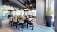 Located at 101 Avenue of the Arts in Wilmington, Delaware, this thoughtfully designed single-floor amenity space blends industrial-chic architecture with sophisticated, contemporary furnishings. The open-plan layout features wide-plank hardwood-style flooring, exposed ductwork, and a dramatic dark ceiling that contrasts elegantly with bright, airy walls and abundant natural light.

The main social lounge offers generous seating arrangements with warmly upholstered chairs and sofas, complemented by a large communal dining table beneath striking pendant lighting. Floor-to-ceiling windows frame serene waterfront views, creating a bright and inviting atmosphere. A dedicated game and entertainment area includes a billiards table, a mounted flat-screen TV, and a casual dining setup — ideal for socializing.

A vibrant private meeting room stands out with bold yellow walls, curated artwork, a round wooden table, houndstooth accent chairs, and a floor-to-ceiling bookshelf, offering an energetic yet functional space for collaboration.

The glass-door entryway makes a polished first impression, featuring textured wall panels, a reception counter, and colorful artwork lining the corridor beyond. Throughout the space, carefully curated art and décor reinforce a cultural, arts-forward identity fitting of its Avenue of the Arts address.