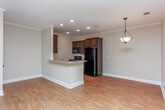 Located in Warner Robins, Georgia, this single-story home offers a thoughtfully designed layout with a blend of comfortable and practical finishes throughout. The open-concept living and dining areas are anchored by warm wood-look flooring, crisp white crown molding, and ceiling fans that add both style and functionality. Natural light filters in through window treatments, enhancing the bright, neutral color palette found in every room.

The kitchen is a standout feature, boasting rich dark-stained cabinetry, granite countertops, a stainless steel sink, and a suite of black appliances including a refrigerator, range, and dishwasher. A peninsula with decorative column accents provides additional prep space and connects seamlessly to the main living area. Recessed lighting overhead ensures excellent illumination throughout.

The bedrooms offer plush carpeting, ceiling fans, and ample natural light from windows with blinds. A dedicated laundry room with wire shelving and dryer hookups adds convenience. The bathroom features a full tub-shower combination, wood-look flooring, and dark vanity cabinetry with granite countertops, maintaining a consistent design aesthetic. This home delivers a clean, move-in-ready environment with practical finishes suited for comfortable everyday living.