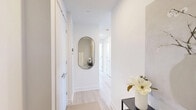 Located at 500 Upper Wellington Street in Hamilton, Ontario, this well-appointed 2-bedroom, 2-bathroom unit offers a thoughtfully designed single-floor layout with a clean, modern aesthetic. Light hardwood flooring and crisp white walls run throughout, creating a bright and cohesive atmosphere across every room.

The entry hallways set a polished tone, featuring an arch-framed mirror, recessed lighting, and an airy, uncluttered flow into the main living areas. The living room offers a comfortable, open feel with neutral walls that invite natural light and provide an ideal backdrop for artwork and furnishings.

The kitchen is a standout feature, showcasing two-tone cabinetry — upper white gloss cabinets paired with warm wood lower cabinets — complemented by light stone countertops, a white tile backsplash, and stainless steel appliances. Floor-to-ceiling windows flood the kitchen with natural light and frame scenic views of the surrounding Hamilton neighbourhood. A central island doubles as a dining and prep space.

The primary bedroom is a serene retreat with direct access to the private balcony through sleek black-framed sliding doors, offering sweeping outdoor views. Both bathrooms are finished with large-format marble-effect tile in the tub and shower surrounds, lending a refined, contemporary look. The second bedroom is bright and neatly proportioned, also with balcony access and light hardwood floors.