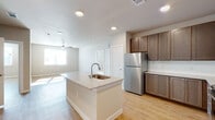 This well-appointed single-floor residence offers a clean, modern aesthetic with a cohesive design throughout. The open-concept kitchen serves as the heart of the home, centered around a granite-topped island with an integrated sink. Rich dark brown cabinetry, a stainless steel refrigerator, and recessed lighting complete the kitchen's polished look. The kitchen flows seamlessly into a bright, open living area with light hardwood-style flooring and a ceiling fan, creating an airy and functional shared space.

The layout also includes an in-unit laundry area tucked conveniently off the main hallway. The bedrooms are generously sized, each benefiting from natural light through blinded windows and ceiling fans overhead. Warm neutral-toned walls and light hardwood floors carry throughout, maintaining a consistent and inviting ambiance.

Storage is a standout feature, with multiple spacious walk-in closets outfitted with wire shelving systems for organized, flexible storage. The bathroom is well-designed, featuring a tiled tub-shower combo, a granite-topped vanity with dark cabinetry, and wood-look flooring. A second vanity area with matching finishes provides additional convenience. Overall, the space balances practicality and modern style in a bright, clean environment.