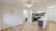 Located at 25100 Ashton Cir in Frankford, Delaware, this one-bedroom, one-bathroom residence offers a thoughtfully designed single-floor layout. Light-toned hardwood-style flooring flows consistently throughout, creating a cohesive and clean aesthetic.

The open-concept kitchen and living area serves as the heart of the home. The kitchen is well-appointed with dark shaker-style cabinetry, granite countertops, a stainless steel refrigerator, electric range, and microwave. A peninsula with pendant lighting above provides additional prep and dining space, while recessed lighting and a ceiling fan complete the living area.

The bedroom is a comfortable, well-lit space featuring a ceiling fan, a window with blinds for natural light, and direct access to a walk-in closet with built-in shelving. Additional closet storage is available throughout the unit, totaling three closets.

The bathroom maintains the same refined aesthetic with dark wood cabinetry, granite-topped vanity, wood-look tile flooring, and a full shower/tub combo. A dedicated laundry area adds everyday convenience. The entry hallway leads smoothly into the main living space, offering a welcoming and organized flow from the moment you step inside.