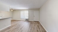 Located in Canoga Park, California, this one-bedroom, one-bathroom unit offers a practical and well-organized single-floor layout. The combined living and kitchen area forms the heart of the space, with light wood-look vinyl flooring throughout and neutral beige walls that create a clean, bright atmosphere. The living room features vertical blinds allowing natural light to filter in, along with a wall-unit air conditioner and a textured popcorn ceiling. A front door provides direct access to the living area, keeping the layout straightforward and functional. The galley-style kitchen is efficiently designed with white cabinetry, granite-look countertops, a stainless steel sink, a gas range, and a full-size refrigerator. Under-cabinet lighting and a ceiling-mounted fixture keep the space well-lit. The bedroom is carpeted for comfort and includes a window with vertical blinds, offering natural light and a textured ceiling consistent with the rest of the unit. The bathroom is finished in white with light wood-look flooring, featuring a toilet and a full tub/shower combination with gold-tone hardware accents. Overall, the unit presents a clean, move-in-ready space with consistent finishes throughout, ideal for those seeking a straightforward and functional living environment in the San Fernando Valley.