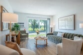 Located at 2321 Traceway Dr in Fitchburg, WI, this single-floor, 2-bedroom, 2-bathroom home offers a thoughtfully designed layout with a clean, modern aesthetic throughout. The open living and dining area is anchored by light wood flooring and large sliding glass doors that flood the space with natural light and frame views of the surrounding greenery, leading directly to a private patio. The living room provides a comfortable, airy atmosphere with generous wall space ideal for artwork and décor. The adjacent dining area features a defined footprint perfect for a round table and seating, with mirrored accents that enhance the sense of openness. The kitchen is complemented by a pantry for additional storage. The primary bedroom is a well-sized retreat finished with plush carpeting, multiple closets, and its own bathroom access. The second bedroom, also carpeted, includes a closet and benefits from ample natural light. Two full bathrooms, including one with white tiled tub surround, serve the residence. A dedicated entrance, hallway, and an impressive five closets throughout ensure practical storage at every turn. The home's bright white walls, black hardware accents, and warm wood tones create a cohesive and inviting ambiance from every angle.