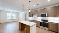 Located at 1455 Moonrise Avenue in Carrollton, TX, this single-story, three-bedroom, two-bathroom home offers a well-designed open layout. The combined kitchen and living area serves as the heart of the home, featuring light wood-style flooring, recessed lighting, and a ceiling fan. The kitchen is equipped with stainless steel appliances—including a range, microwave, and French door refrigerator—complemented by warm wood-toned cabinetry, a white subway tile backsplash, and a central island with a white countertop and pendant lighting overhead. The bedrooms offer a comfortable, neutral aesthetic with plush carpeting, ceiling fans, and windows with blinds that allow natural light. Two closets provide organized storage, including a walk-in closet accessible from one of the bathrooms. The two bathrooms are well-appointed: one features a glass-enclosed walk-in shower with tile surround, while the other offers a full soaking tub with a shower, white tile surround, and built-in shelving. Light wood-style flooring carries through the bathrooms for a cohesive look. The overall design is clean and modern, with a neutral color palette that creates a bright, welcoming atmosphere throughout.
