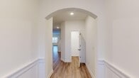 This two-story home in Athens, Alabama offers a thoughtfully designed layout spread across two floors, providing ample space for comfortable living. The main level welcomes you through an elegant entrance highlighted by a graceful arched doorway framed by classic wainscoting and recessed lighting, with warm hardwood-style flooring flowing throughout. The combined kitchen and living room serves as the heart of the home, featuring stainless steel appliances, warm-toned cabinetry, granite-look countertops, a kitchen island, and a window that brings in natural light. The main floor also includes a convenient laundry room with full-size washer and dryer hookups, and direct access to the attached garage, which features a concrete floor and an integrated water heater. Upstairs, four bedrooms offer generous proportions, each with hardwood-style flooring and access to closet space. The spacious primary bedroom includes a dedicated walk-in closet outfitted with wire shelving for ample storage. The two bathrooms are finished with clean white fixtures, granite-look vanities, and tub-shower combinations with chrome hardware. Throughout the home, neutral white walls, recessed lighting, and consistent flooring create a cohesive and move-in-ready aesthetic.